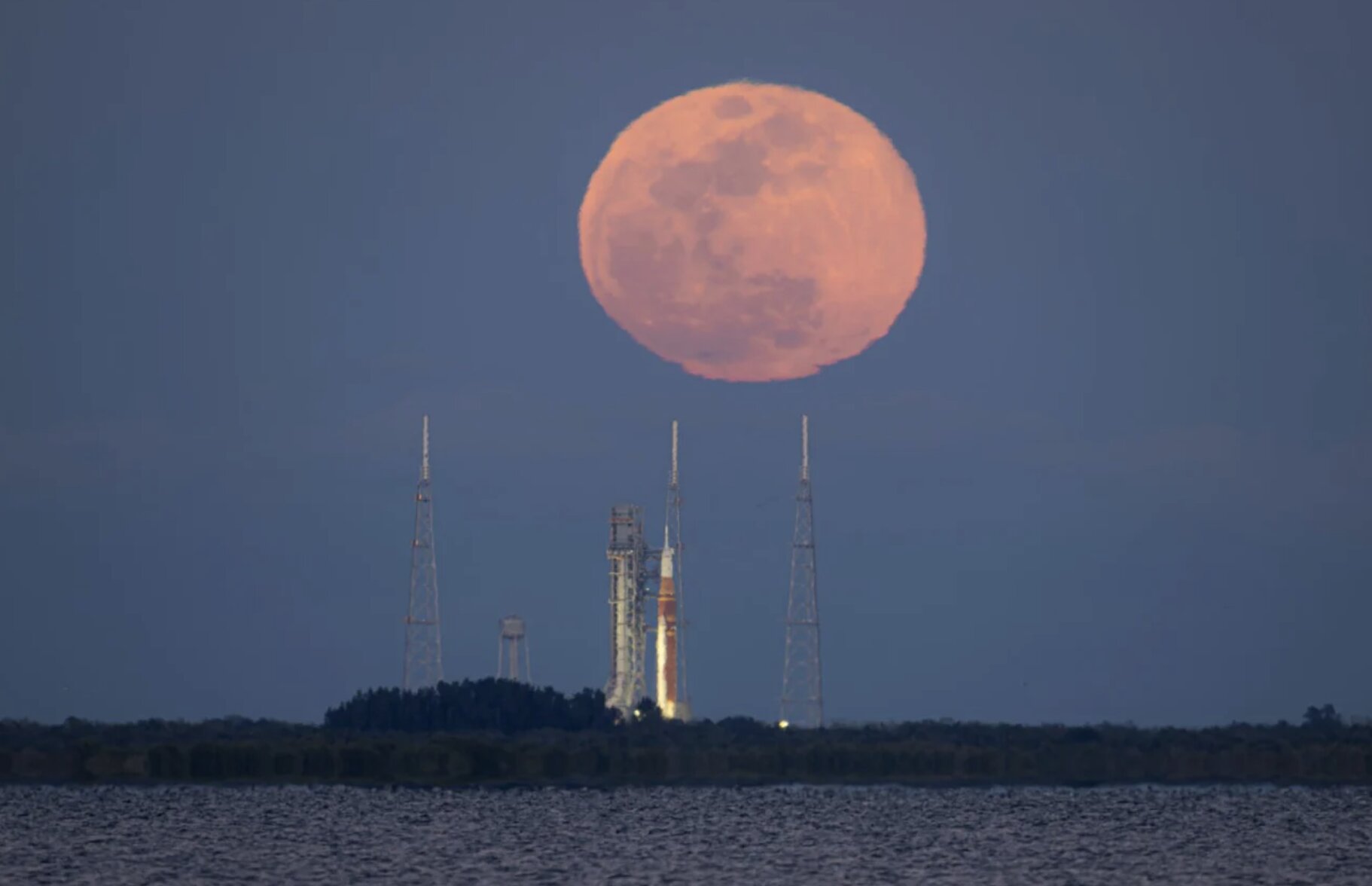 Full moon rising behind Artemis II rocket before rehearsal, editorial image for Moon mission coverage